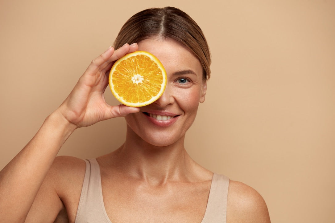 A lady holding an orange over her face