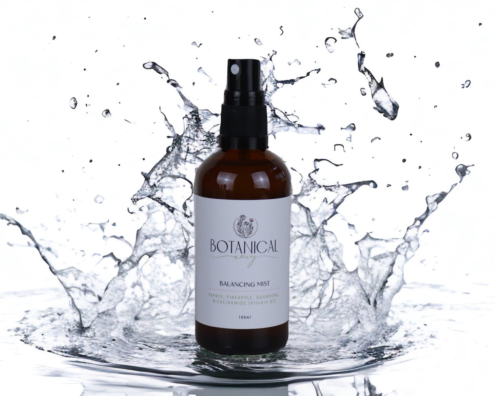 An amber glass bottle of balancing mist with water splashing around it