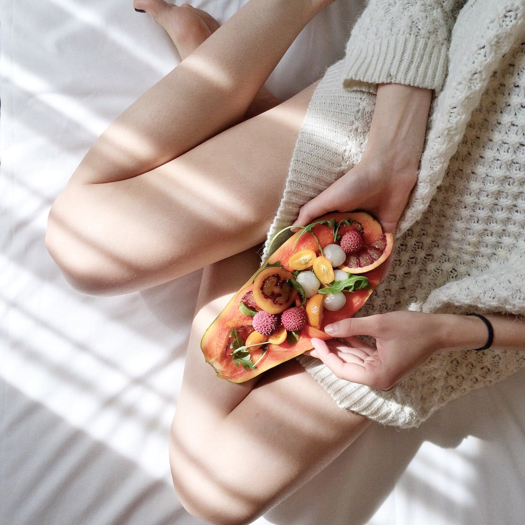 A lady holding a bright coloured fruit salad