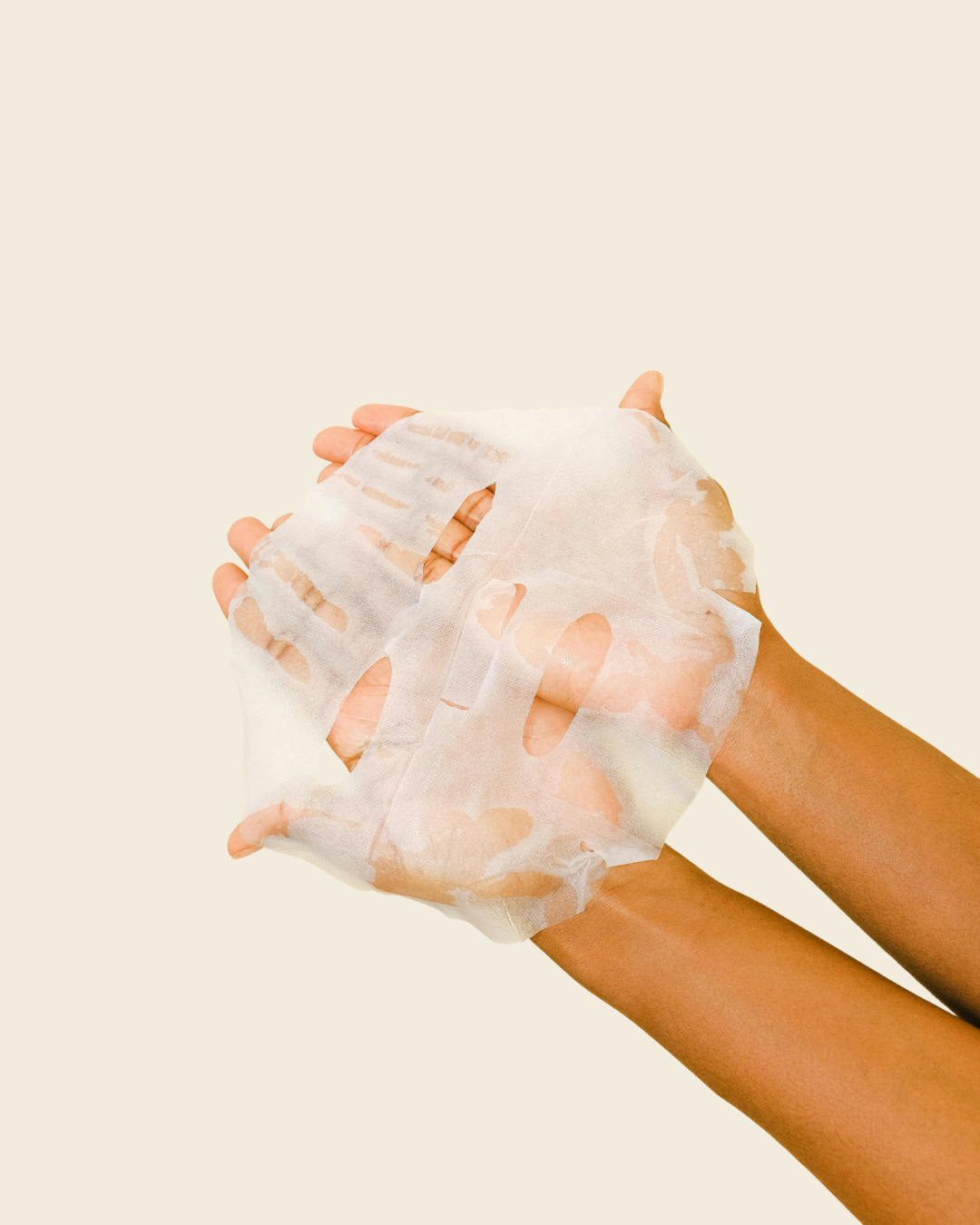 A women hold a face sheet mask against a light beige background