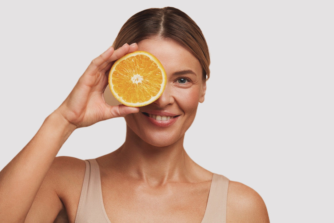 A blond lady holding an orange cut in half