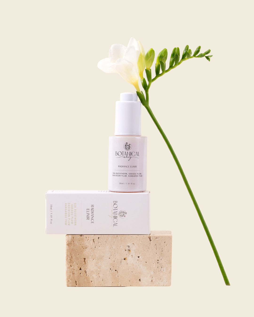 A white bottle of Radiance elixir sitting on the serum packaging and a rectangular stone with a white flower placed against a beige background.