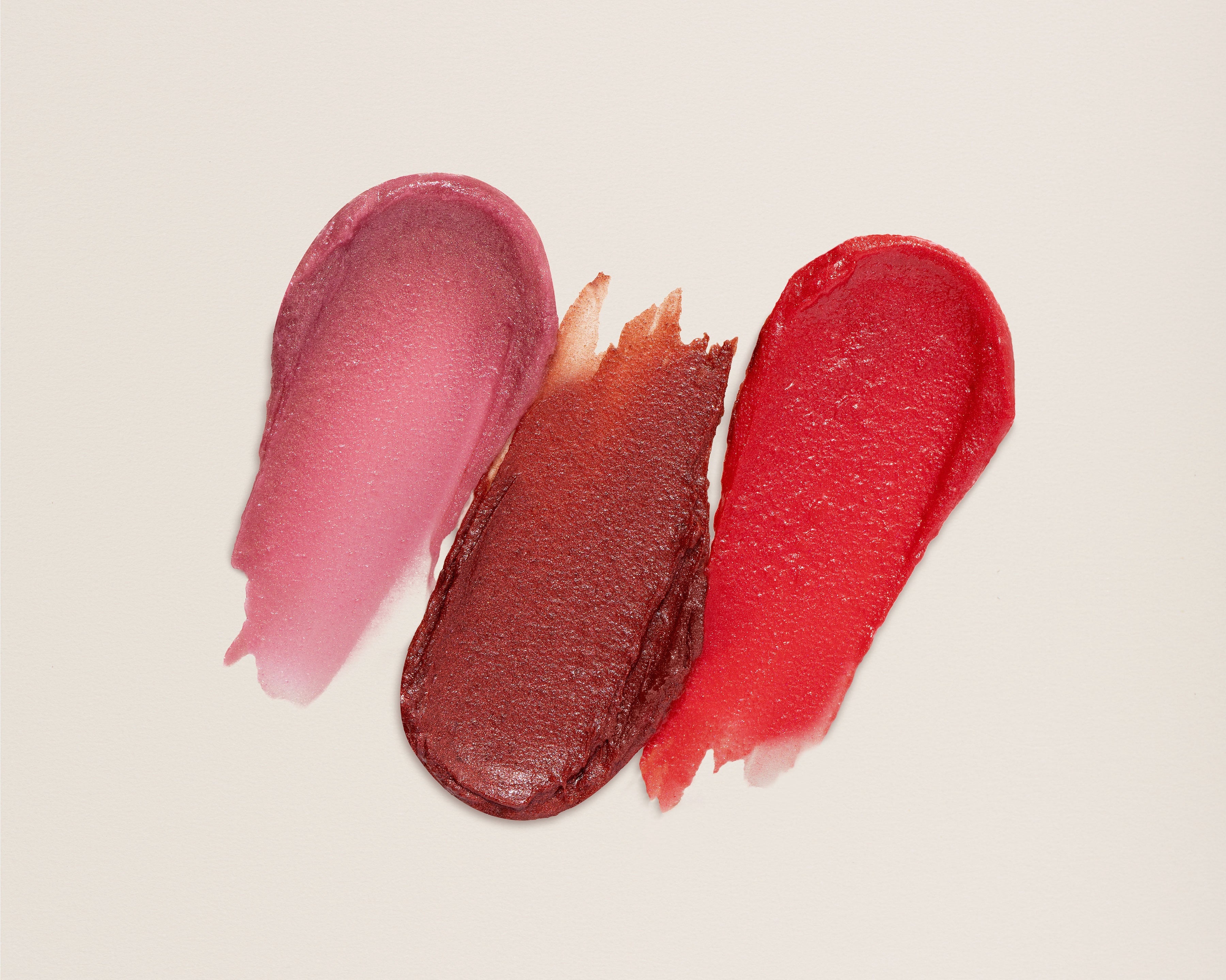 Three swatches of different lip tints on a beige background